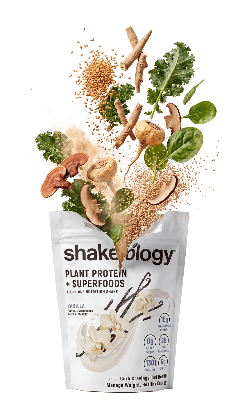 Shakeology Plant Protein + Superfoods pouch, shown with roots, seeds, mushrooms, and greens bursting from the top.